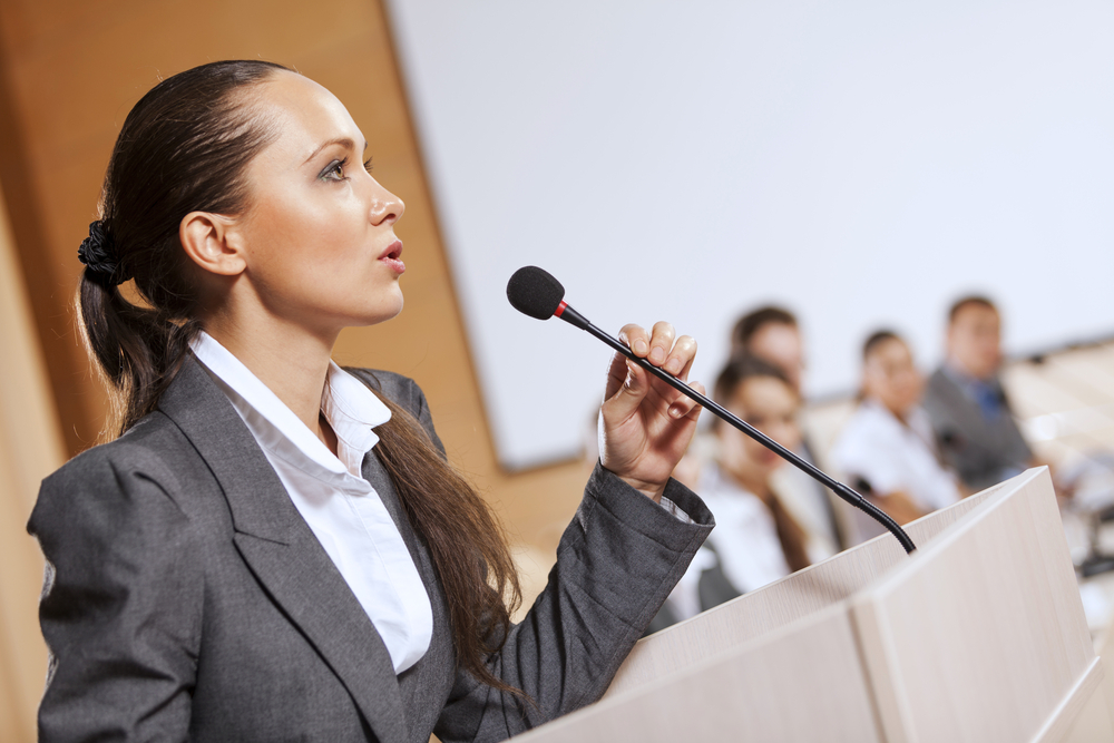 Businesswoman standing on stage and reporting for audience