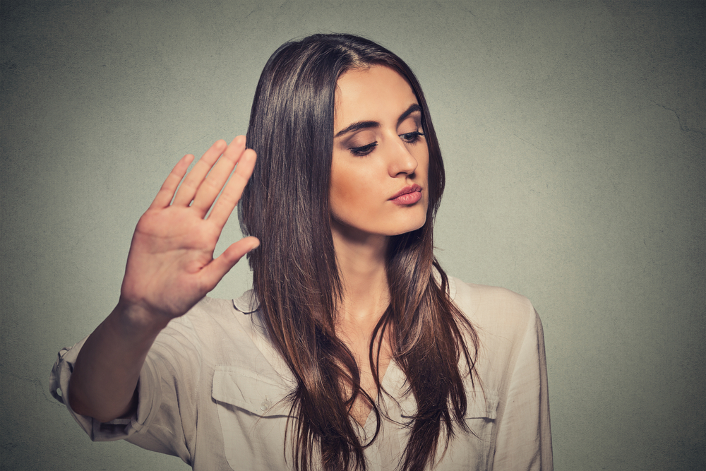 Closeup portrait young annoyed angry woman with bad attitude giving talk to hand gesture with palm outward isolated grey wall background. Negative human emotion face expression feeling body language