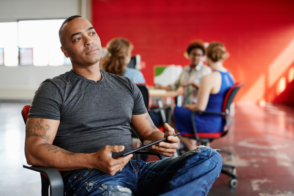 Confident male designer working on a digital tablet in red creative office space