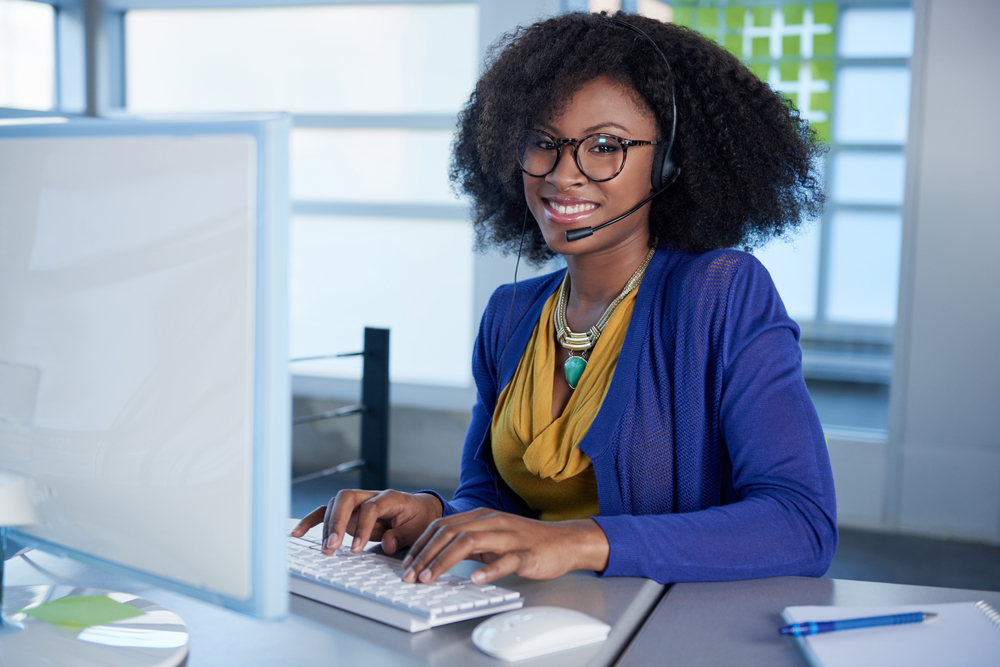 Portrait of a smiling customer service representative at the computer using headset