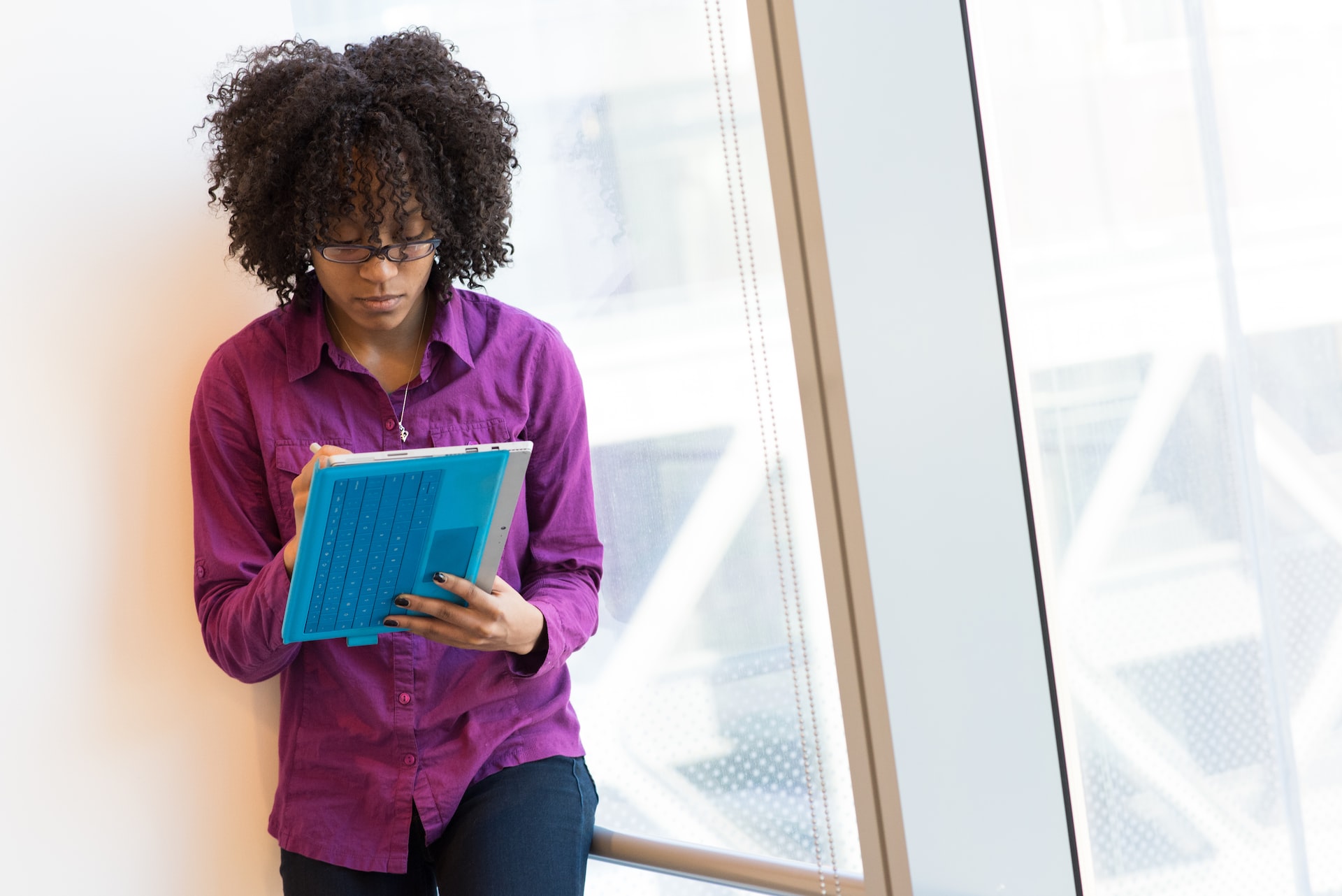 woman looking at notebook standing by window