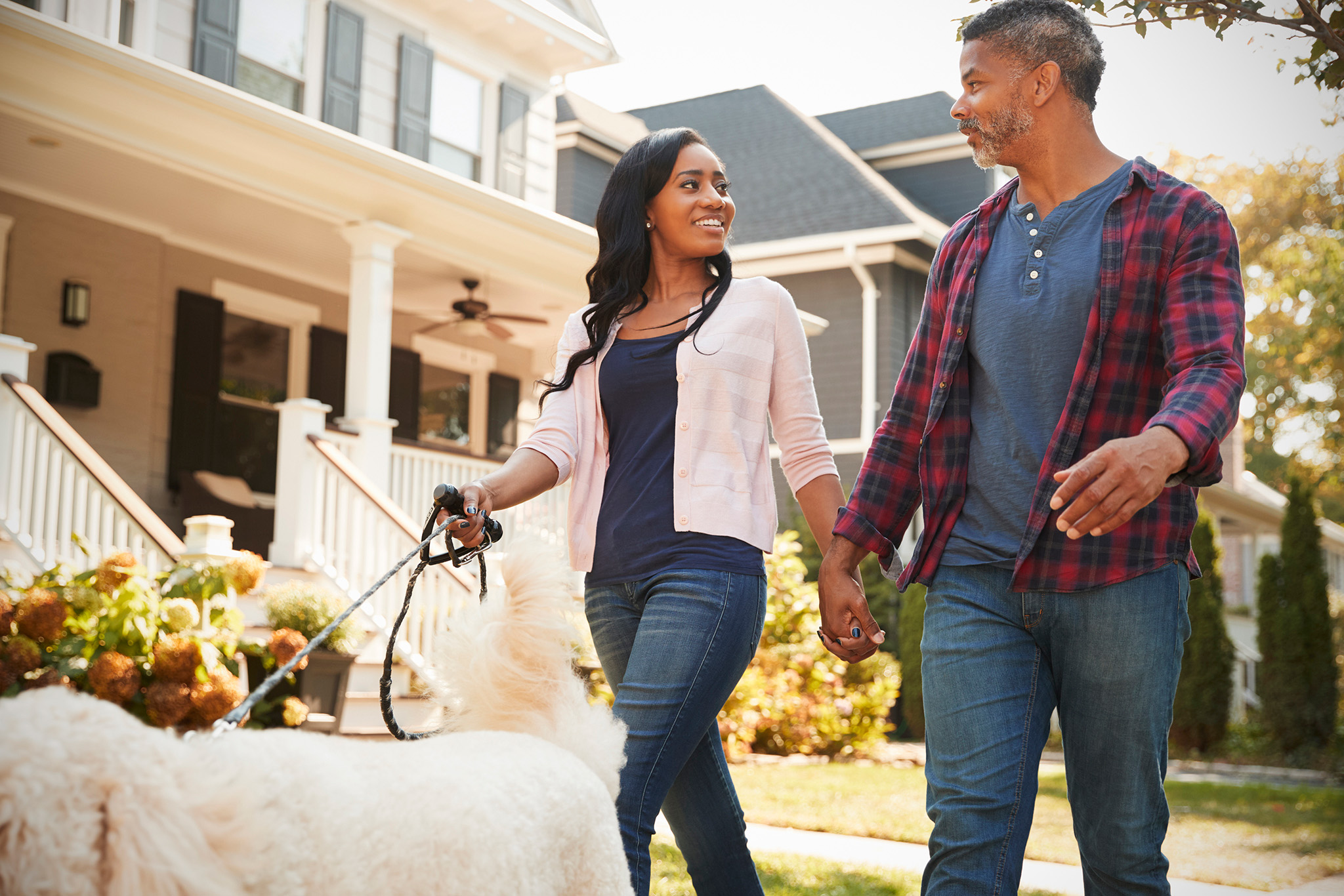 couple-walking-dog-along-suburban-street-PLH8K3F