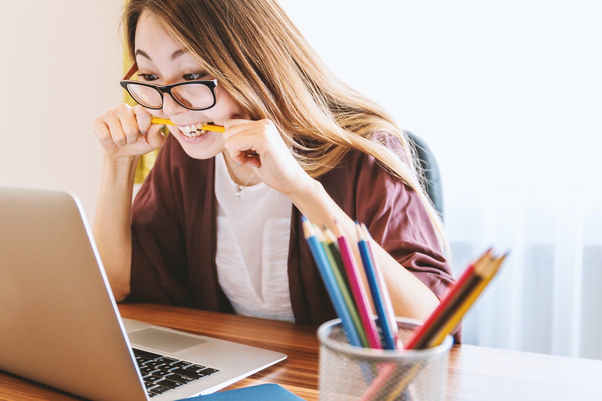 person looking at laptop in frustration and biting their pencil