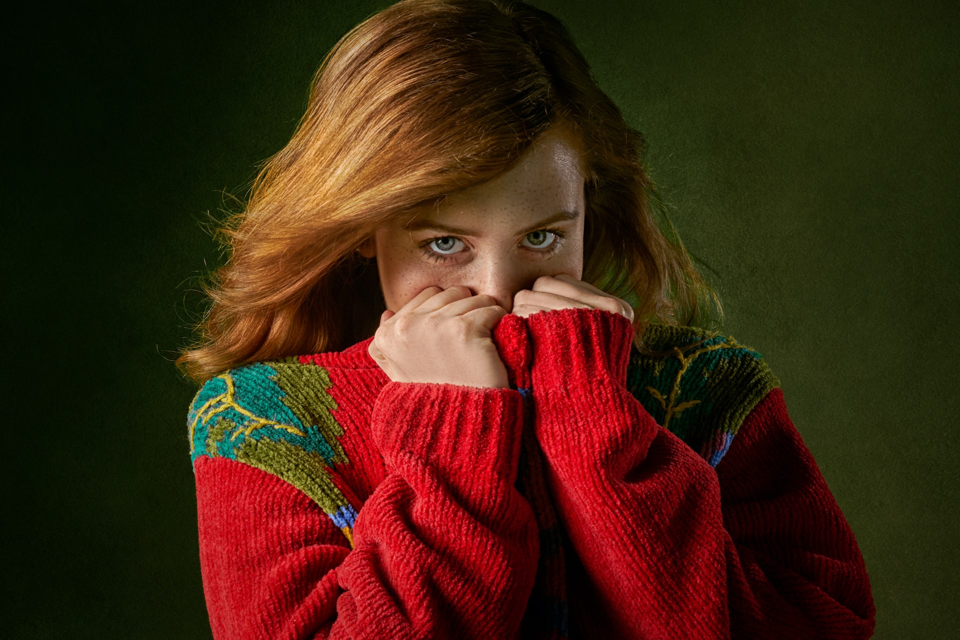 woman covering face while wearing holiday sweater