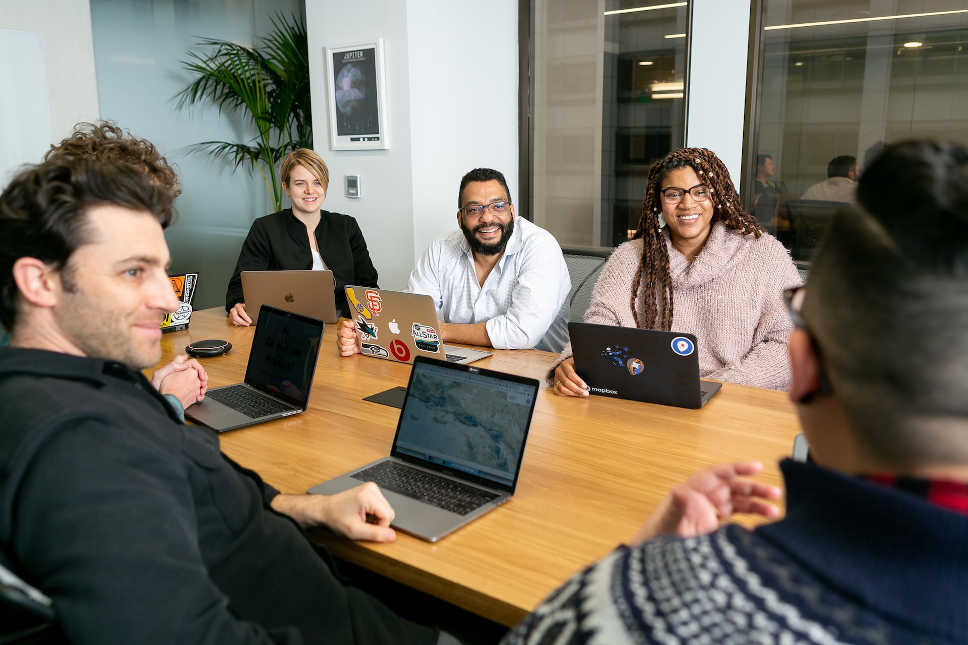 people sitting around a conference table smiling with laptops